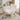 White rocking chair in a room with a bookshelf, lamp, and plant.